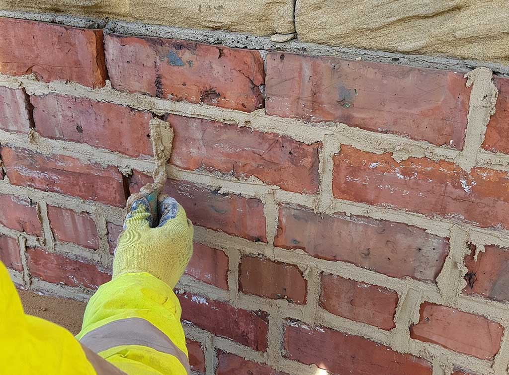 Brickwork being repointed with fresh lime mortar